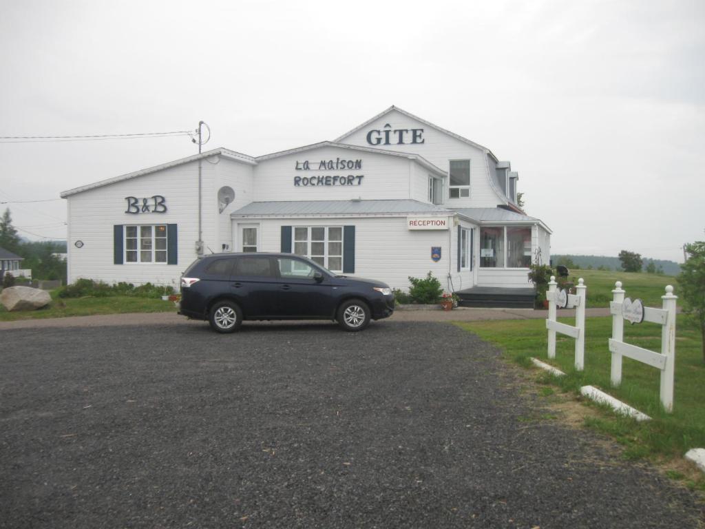 a black car parked in front of a white building at Gite la Maison Rochefort in Baie-Sainte-Catherine