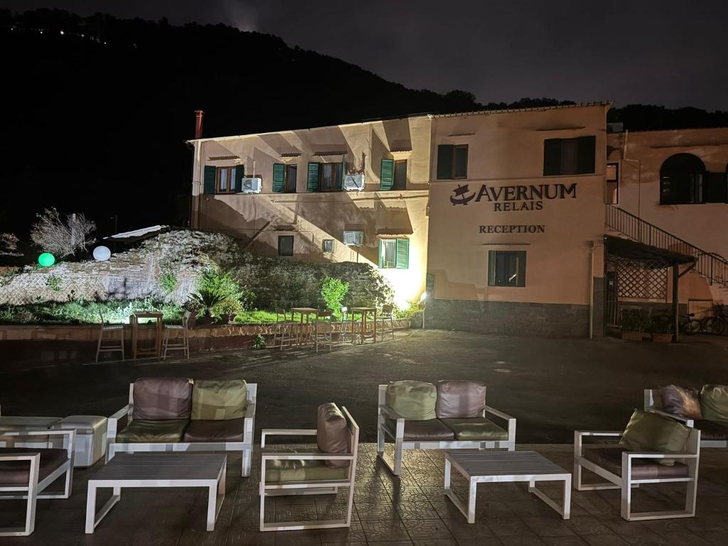a group of chairs in front of a building at night at Avernum Relais Hotel e Ristorante in Pozzuoli