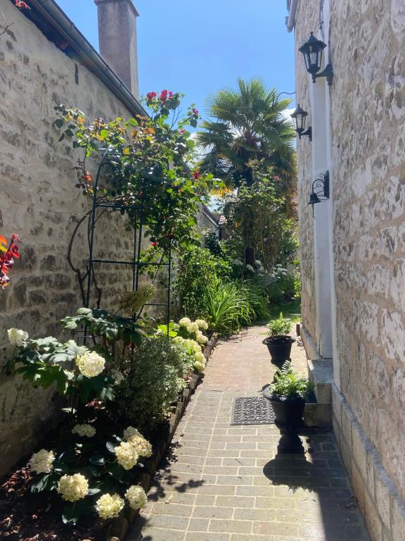 Une allée avec des fleurs et des plantes dans un bâtiment dans l'établissement Maisonnette individuelle au coeur de Vernon, à Vernon