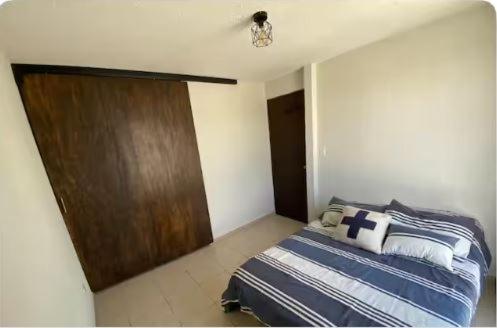 Un dormitorio con una cama y una puerta de madera. en Habitación para descansar, en Tijuana