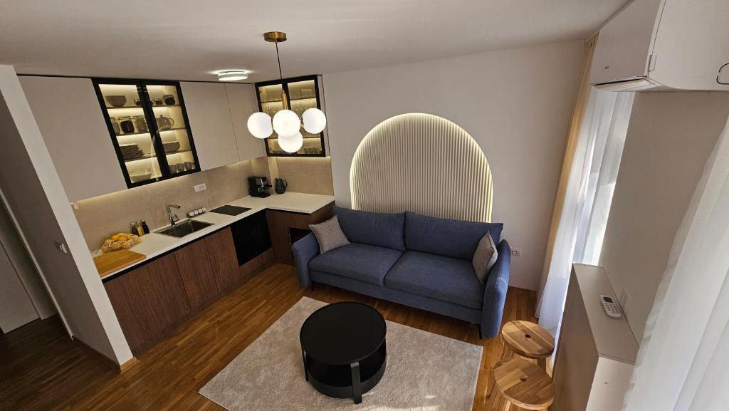 a living room with a blue couch and a kitchen at Sila apartman Vrnjačka Banja in Vrnjačka Banja
