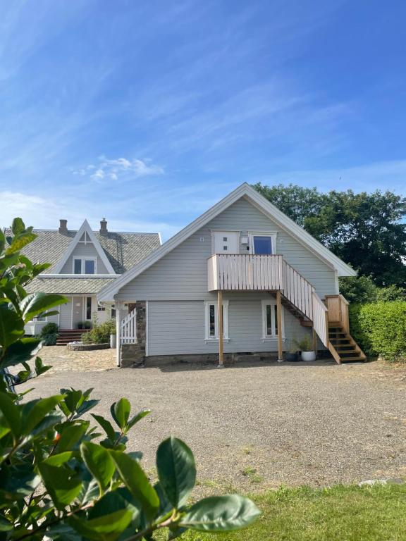 a large white house with a porch and stairs at Havbris apartment with sea view in Borhaug, Farsund in Borhaug