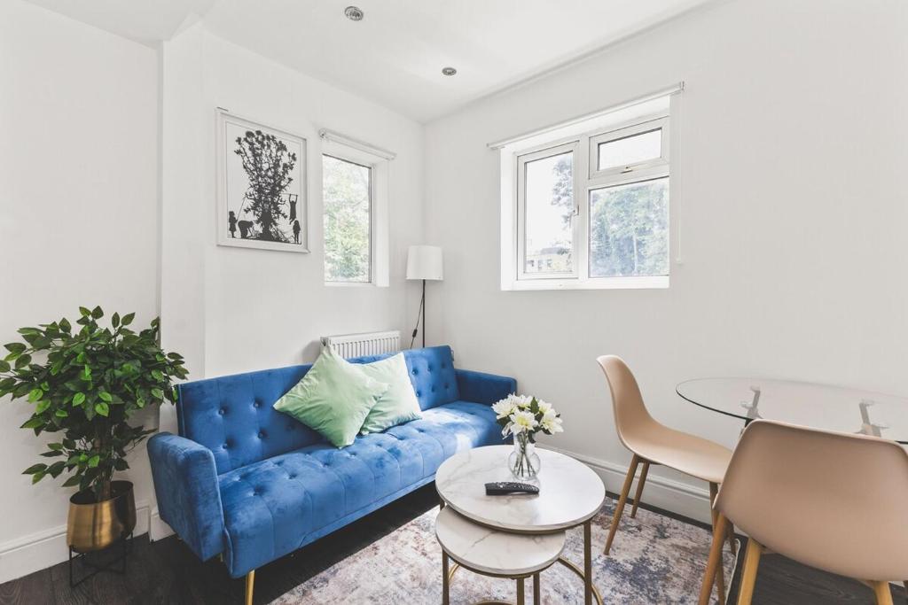 a living room with a blue couch and a table at Modern 2bed flat near station - COU B in Coulsdon