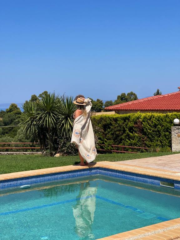 a woman is standing next to a swimming pool at Villa Elpida in Kriopigi