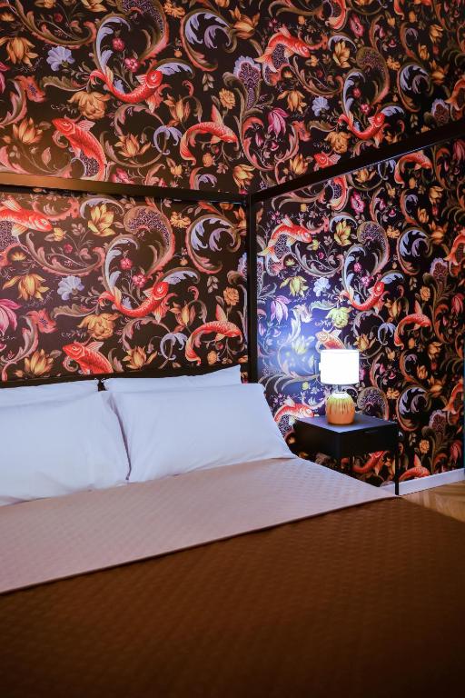a bedroom with a bed and a wall covered in wallpaper at Via Manno 11 Rooms in Iglesias