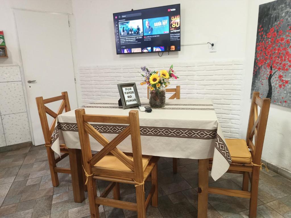 una mesa con un jarrón de flores y una TV en la pared en Departamento Familiar con estacionamiento incluido, en Bahía Blanca