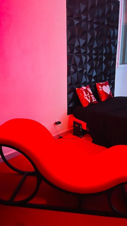 a red couch in a room with a pink wall at Vénus #Love room# in Capesterre-Belle-Eau