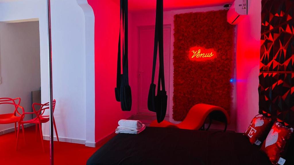 a red room with a table and chairs and a neon sign at Vénus #Love room# in Hoguet