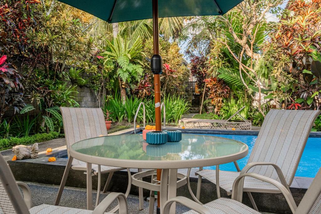 a glass table with an umbrella on a patio at Pondok Alami Villas 5BR & Pool in Ubud
