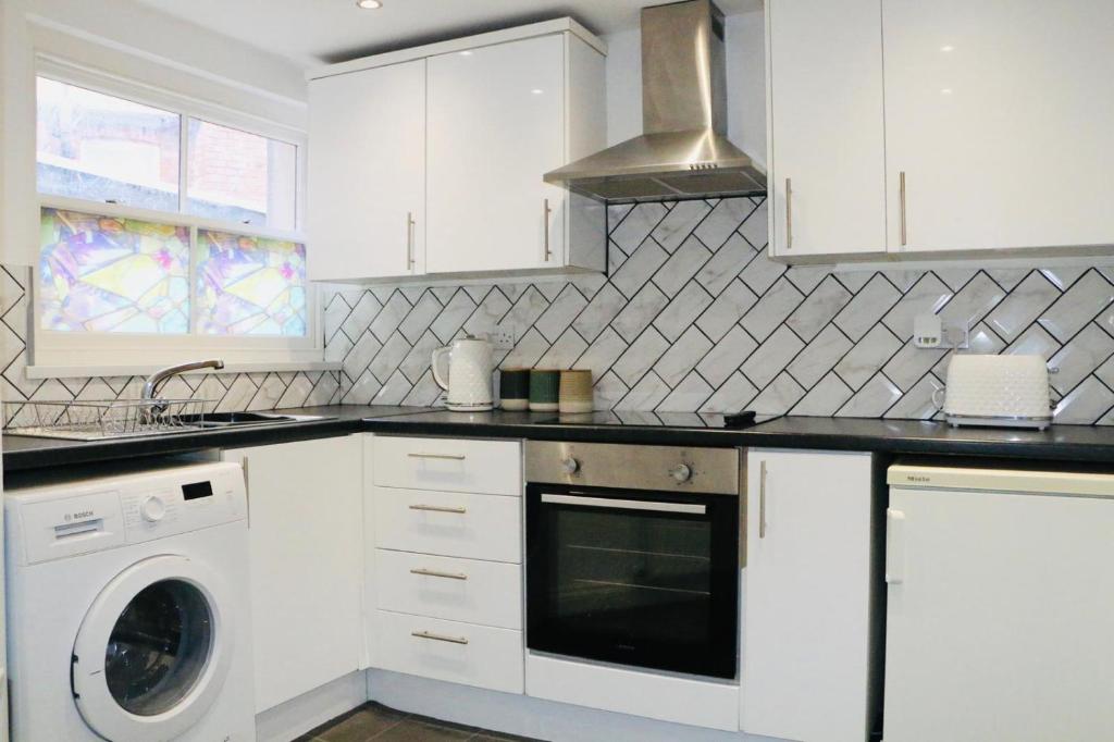 a kitchen with white cabinets and a washer at apartment block- great for contractors in Hull