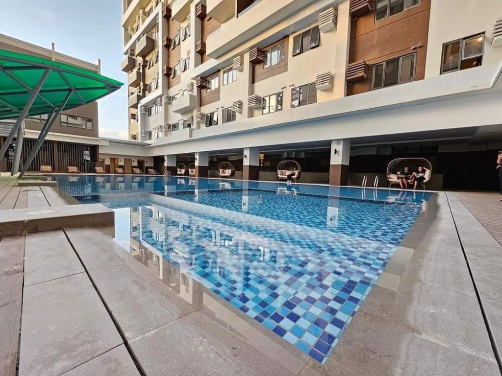 a large swimming pool in front of a building at Cozy 1 bedroom at BE Residences Condominium with balcony near IT Park in Tabok