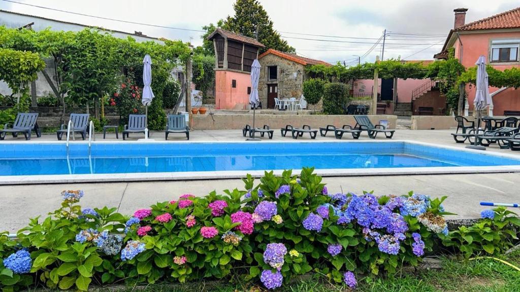 a swimming pool with flowers in front of a house at Quintinha de Santiago in Oliveira de Azemeis