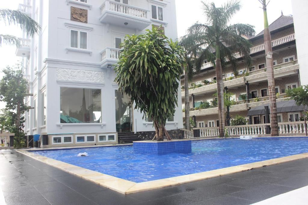 a large swimming pool with a tree in front of a building at Hoang Thanh Thuy 3 Hotel in Ho Coc