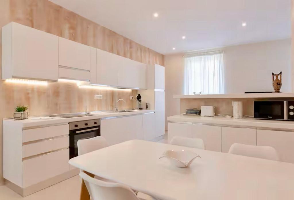 une cuisine avec des armoires blanches et une table et des chaises dans l'établissement 3 ROOMS - DOWNTOWN CANNES - 2 MIN FROM PALAIS Festivals, à Cannes