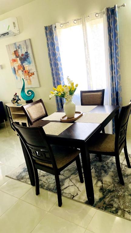 a dining room table with chairs and a vase of flowers on it at Jamaica Coastal Getaway in Discovery Bay