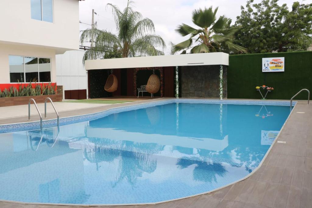 a swimming pool with blue water in front of a building at Hotel Pikeiro Blue in Manta