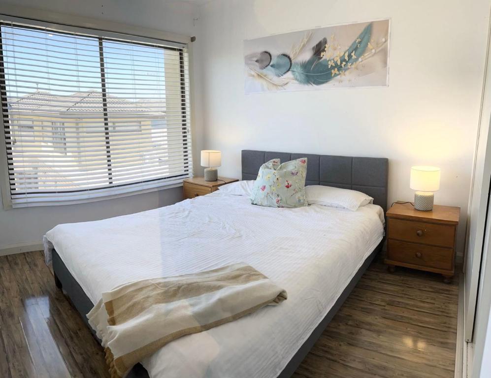 a bedroom with a large white bed with two lamps at Room Close Melbourne Airport in Melbourne