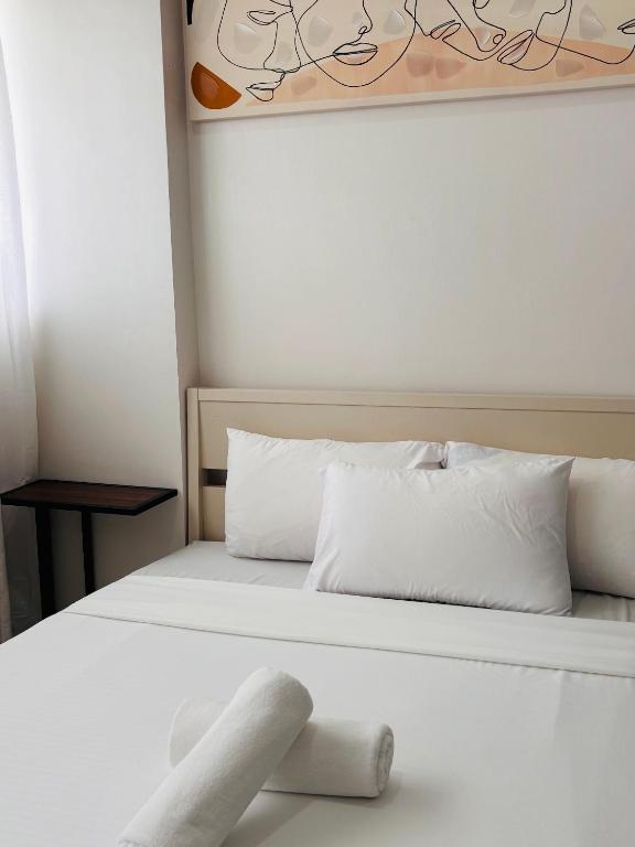a white bed with white pillows and a painting at Minimalist Comfort Modern Stay Cozy Vibes in Iloilo City