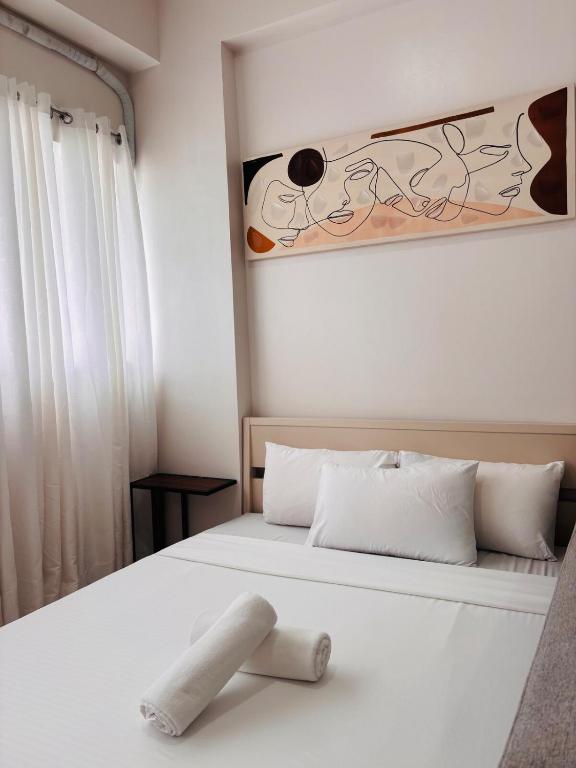 a bedroom with a white bed with a painting of a dog at WV 11 Light & Fresh Studio in Iloilo City