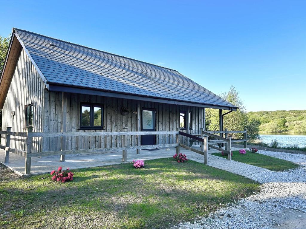a wooden cabin with flowers in front of it at Kingfisher Lodge in St Austell