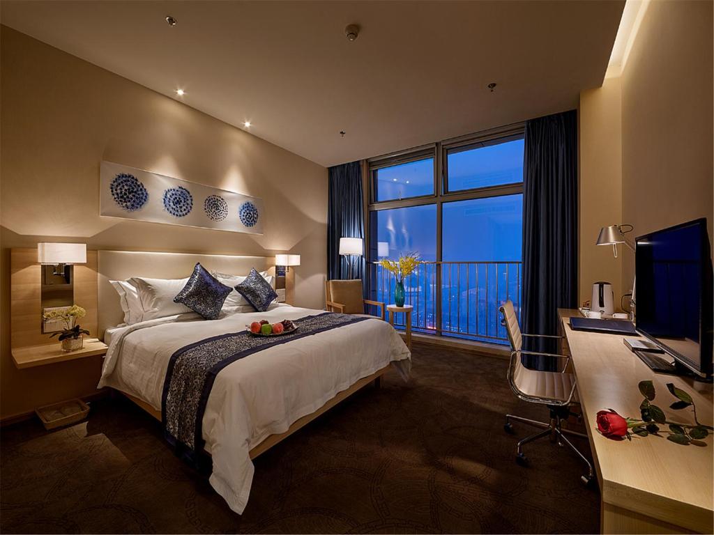 um quarto com uma cama, uma secretária e uma televisão em 石家庄诺华廷酒店 Novlion hotel em Shijiazhuang