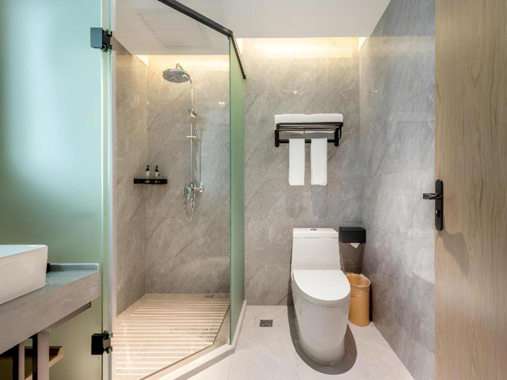 a bathroom with a shower and a toilet and a sink at Echarm Hotel Guangzhou North Station Cultural Tourism City in Huadu