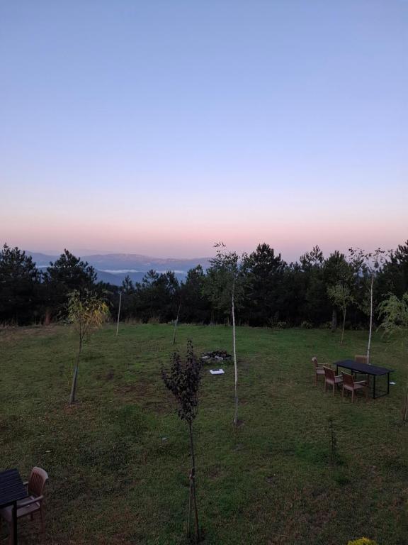 two picnic tables and benches in a field with the sunset at Vila Alpine Arlon Gjinar in Gjinar