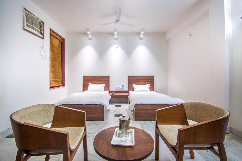 a bedroom with two beds and a table and chairs at Hotel Bhakti Dhama in Vrindāvan