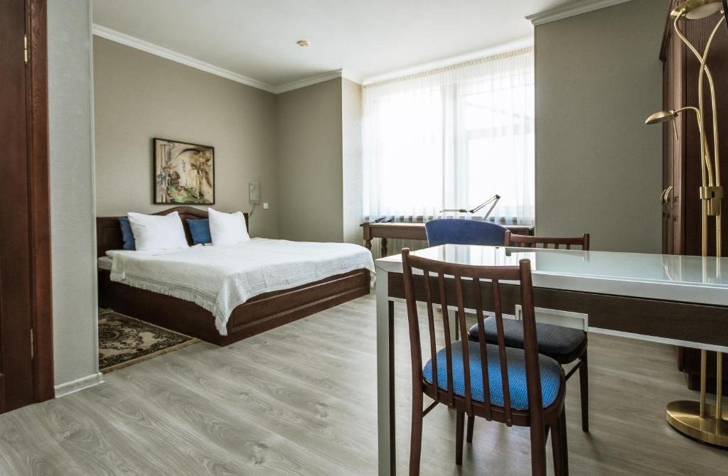 ein Hotelzimmer mit einem Bett, einem Schreibtisch und einem Tisch in der Unterkunft Hotel Kert FREE PARKING in Riga