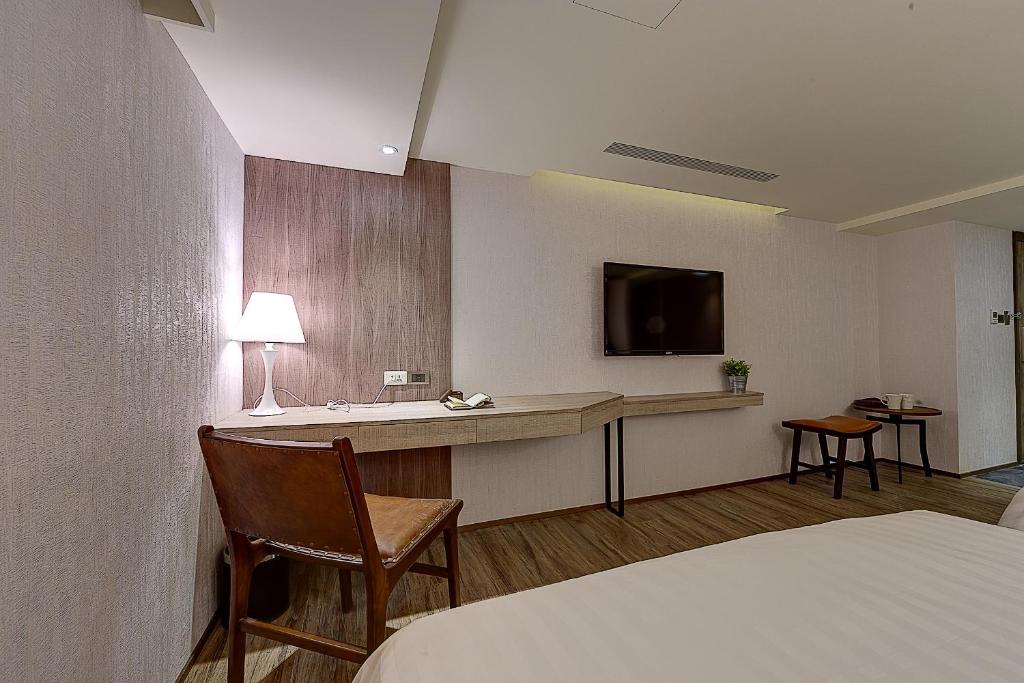 a hotel room with a bed and a desk with a television at Lan Kwai Fong Garden Hotel in Chiayi City