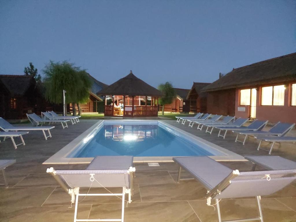 a swimming pool with lounge chairs around it at La Tavi casute tip camping in Murighiol