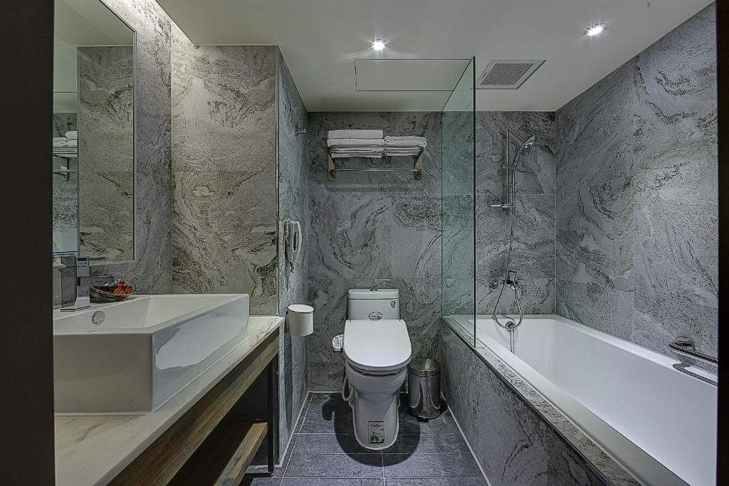 a bathroom with a toilet and a tub and a sink at Lan Kwai Fong Garden Hotel in Chiayi City