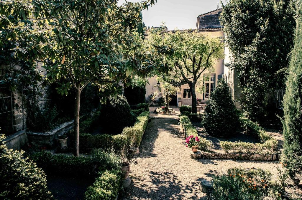 un jardin avec des arbres et des fleurs et un bâtiment dans l'établissement Hotel de L Orange, à Sommières