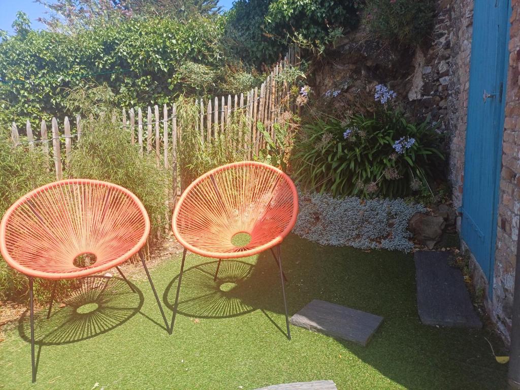 due sedie arancioni appoggiate sull'erba in un cortile di Maison de ville cosy avec jardin, à 300 m de la plage & restaurants a Binic