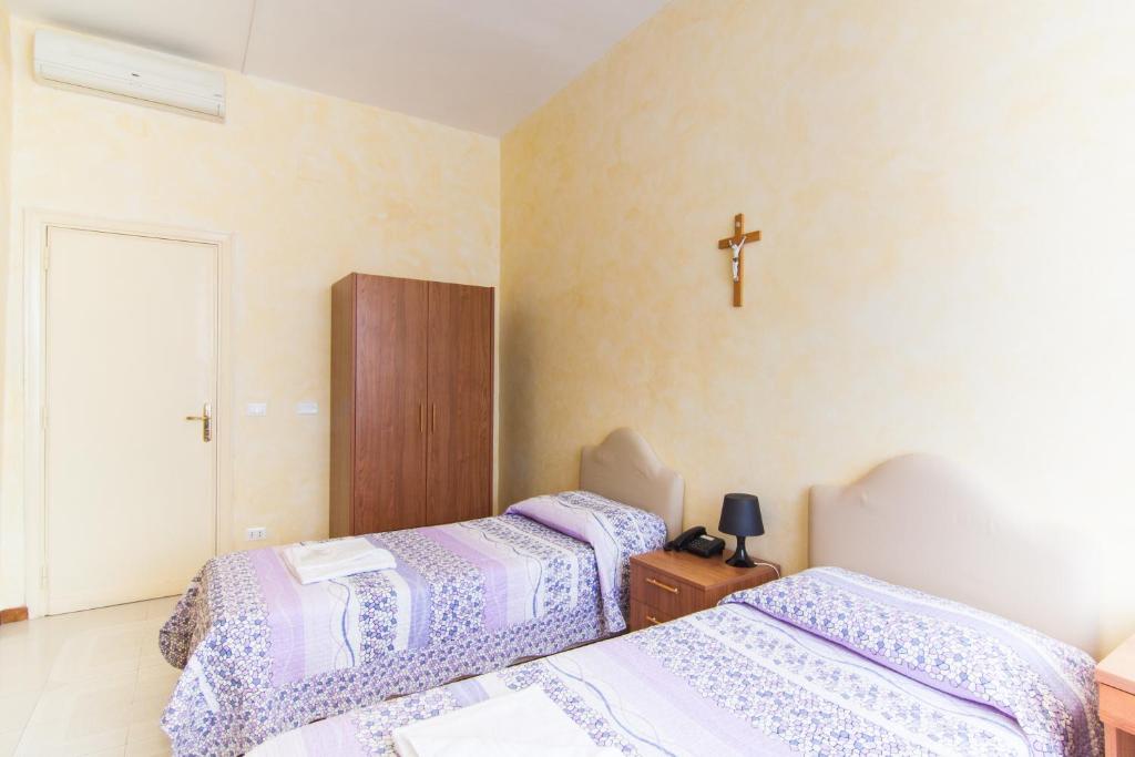 two beds in a room with a cross on the wall at Ostello Villa Monte Mario in Rome