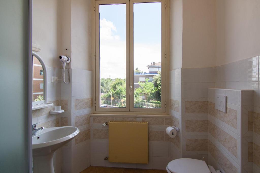 a bathroom with a sink and a toilet and a window at Ostello Villa Monte Mario in Rome