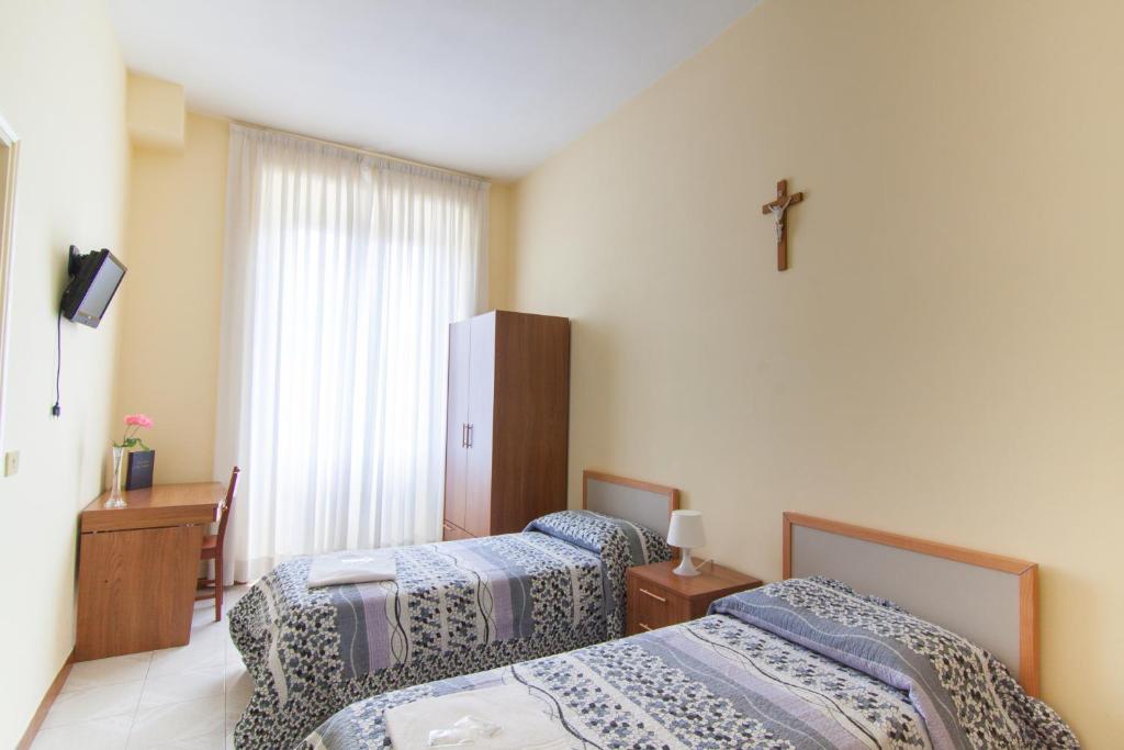 a bedroom with two beds and a cross on the wall at Ostello Villa Monte Mario in Rome