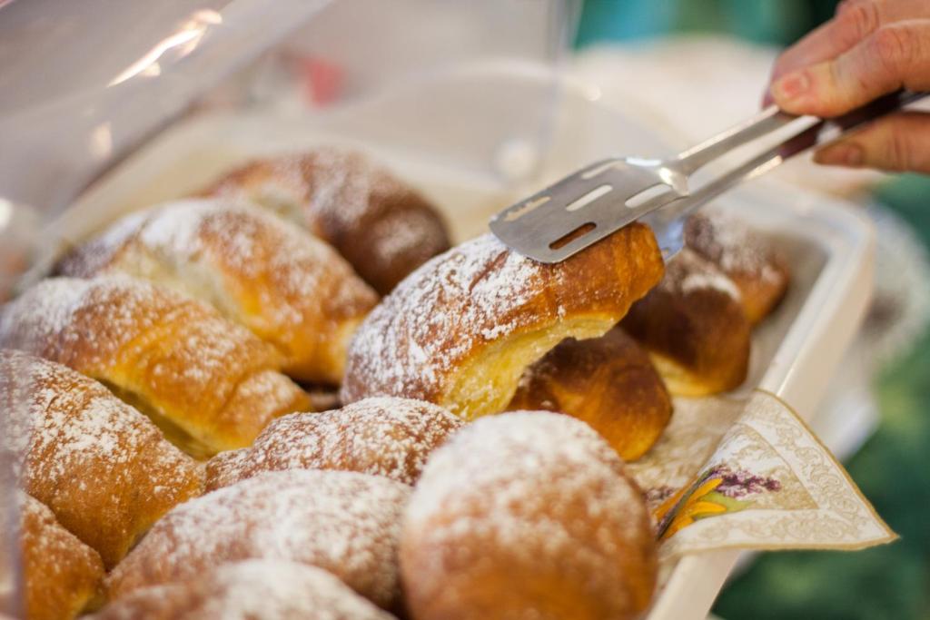 a person is reaching for a tray of donuts at Ostello Villa Monte Mario in Rome