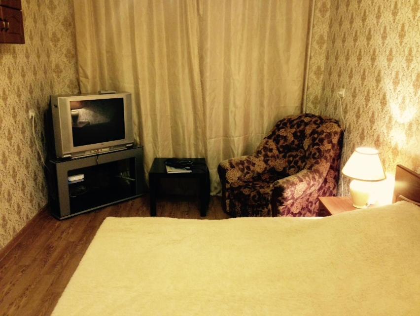 ペルミにあるApartment Kim 83のテレビ、椅子が備わるホテルルームです。