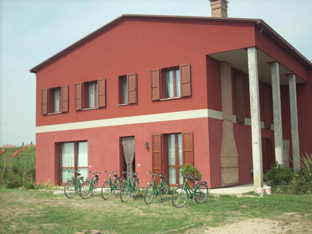 ein rotes Haus mit Fahrrädern, die draußen geparkt sind in der Unterkunft B&B Da Toni in Taglio di Po
