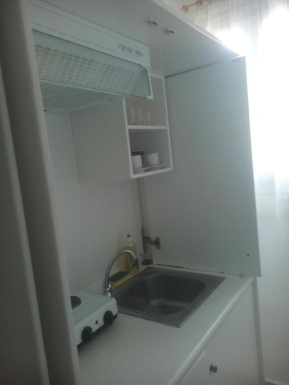małą białą kuchnię ze zlewem i kuchenką w obiekcie Karagiozos Studios & Apartments w mieście Skopelos