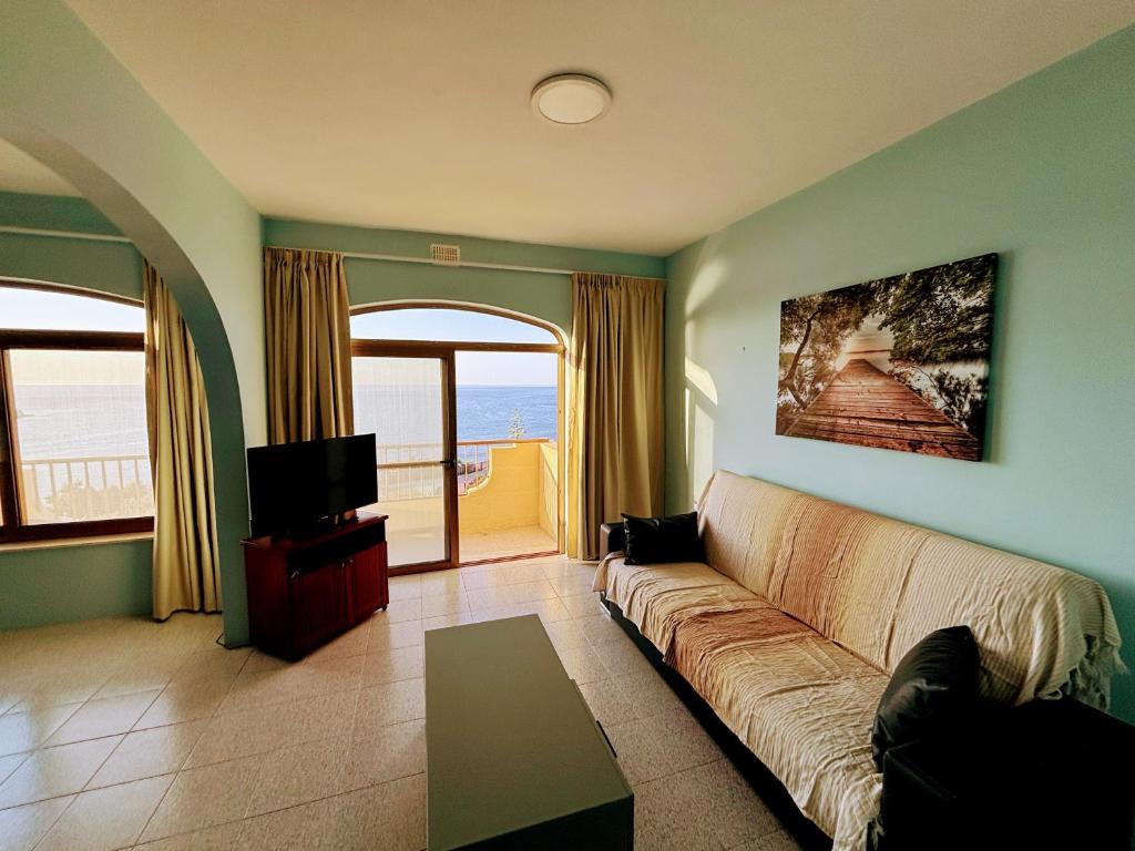a living room with a couch and a tv at SeaView Sunset Gozo in Marsalforn