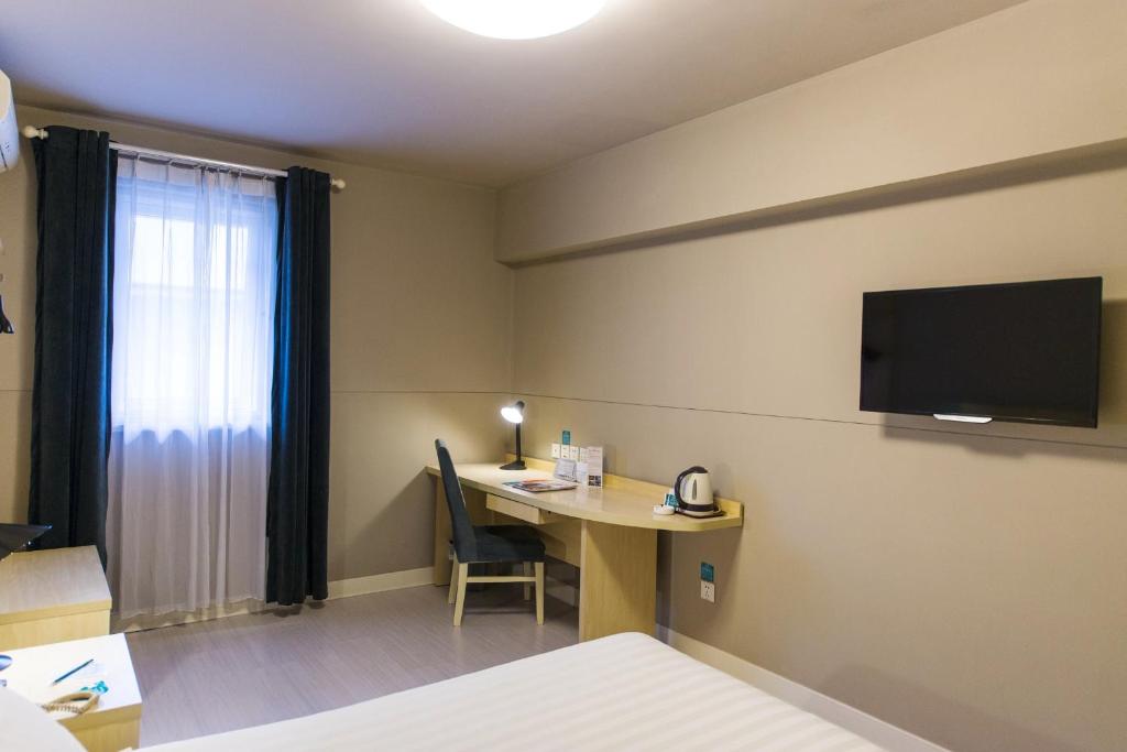 a hotel room with a desk and a tv on the wall at Jinjiang Inn Shantou Jinsha Road Bus Station in Shantou