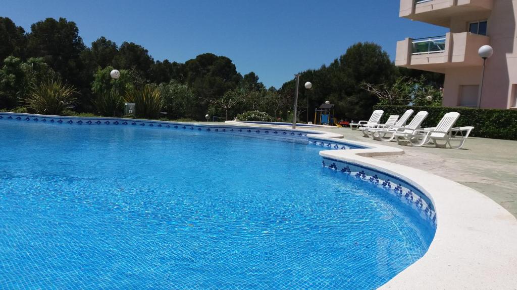 a large swimming pool with chairs next to a building at Apartamento Cap de Salou in Salou