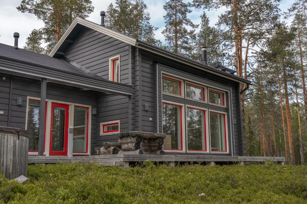 a black house with red windows in the woods at 2-Wing Villa 4BR, 2 SkiPasses, Ylläs & Nature View in Ylläsjärvi