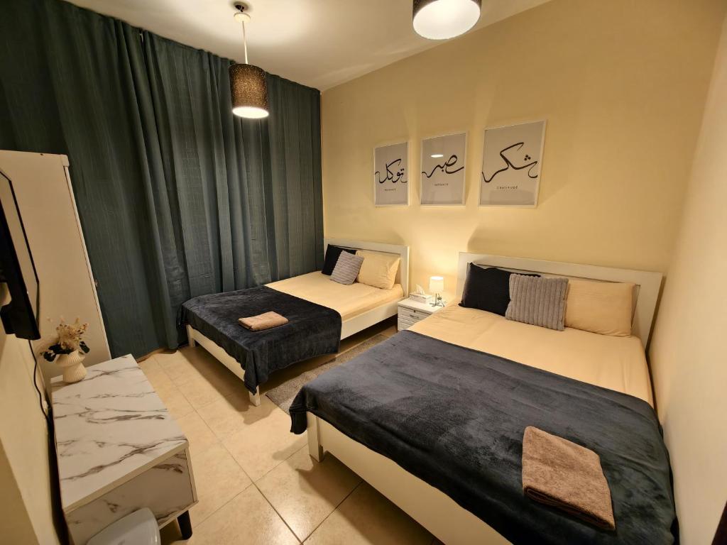 una piccola stanza con due letti e un tavolo di TheGrid-HomeStay a Abu Dhabi
