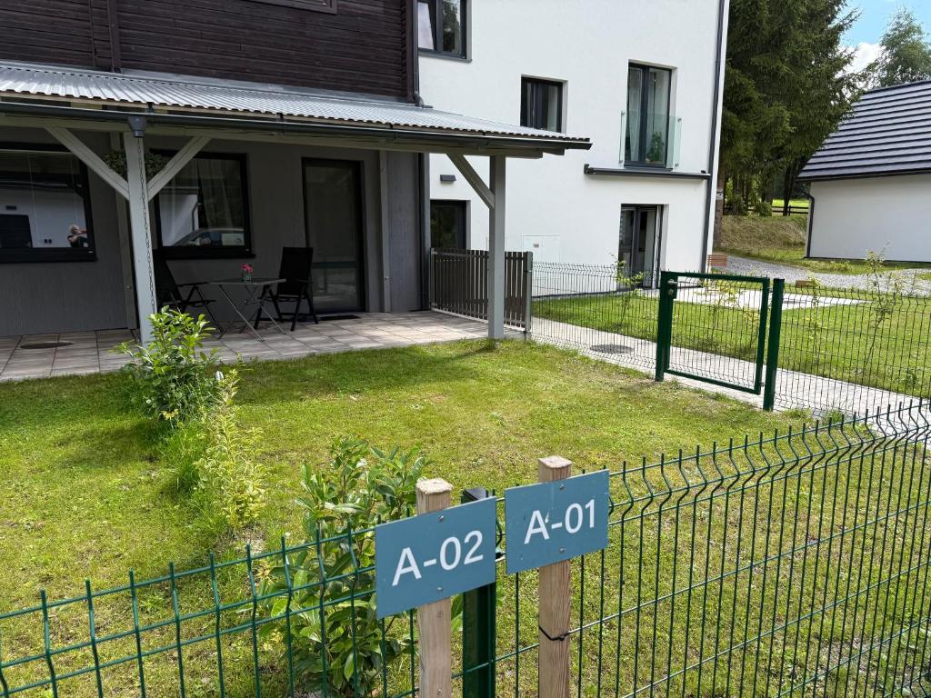a fence in front of a house with a yard at Náš Sen - Apartmán in Svratouch