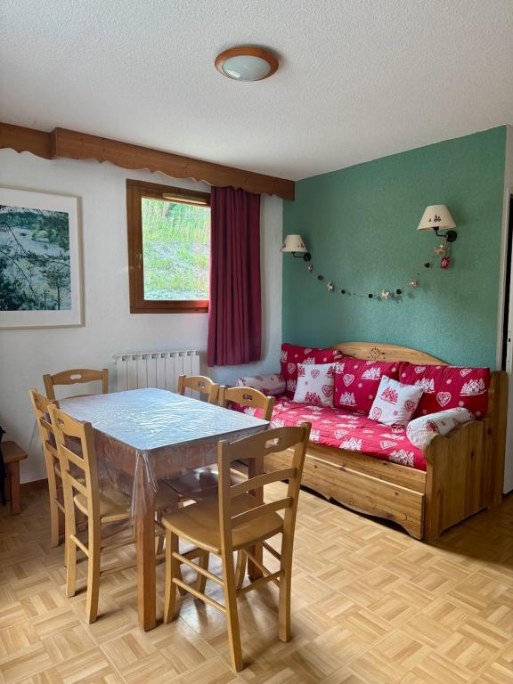 un salon avec une table et un canapé rouge dans l'établissement Puy St Vincent 1800 - appt 6 pers - près des pistes, à Puy-Saint-Vincent