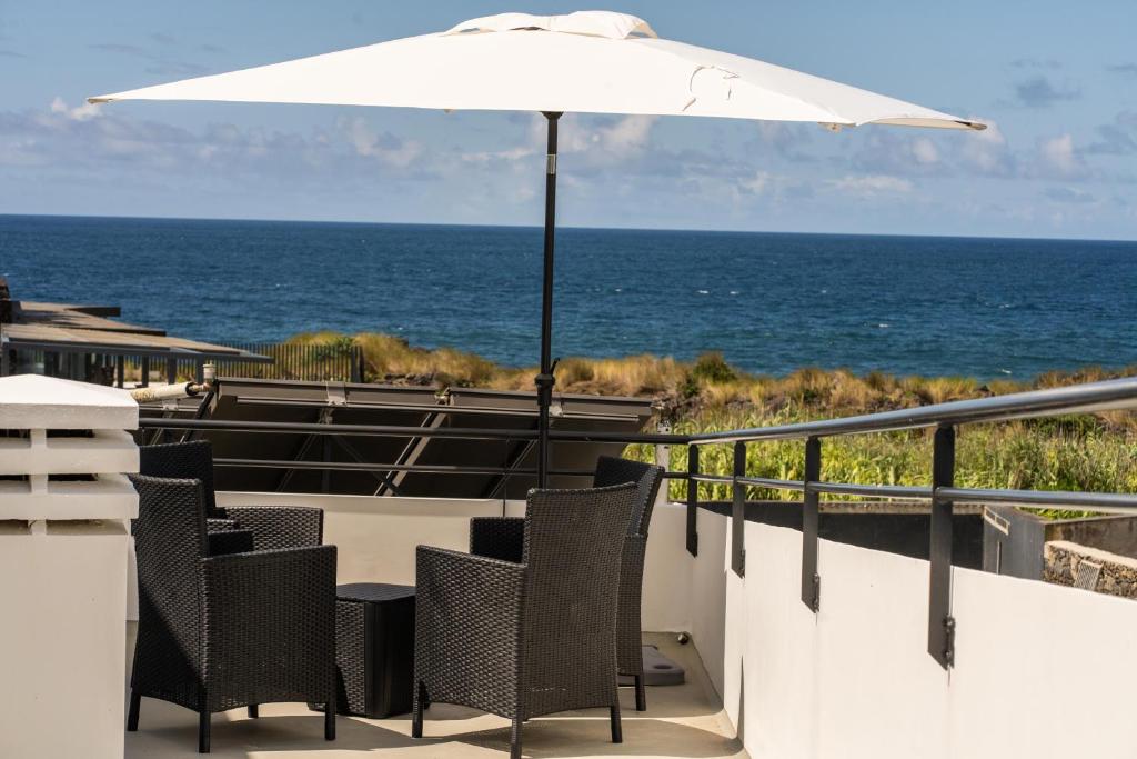 a patio with chairs and an umbrella and the ocean at Oceanside Village 4 in Lagoa