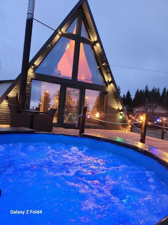 a house with a star shaped window and a pool at Cabana Golden Sunset in Mărişel